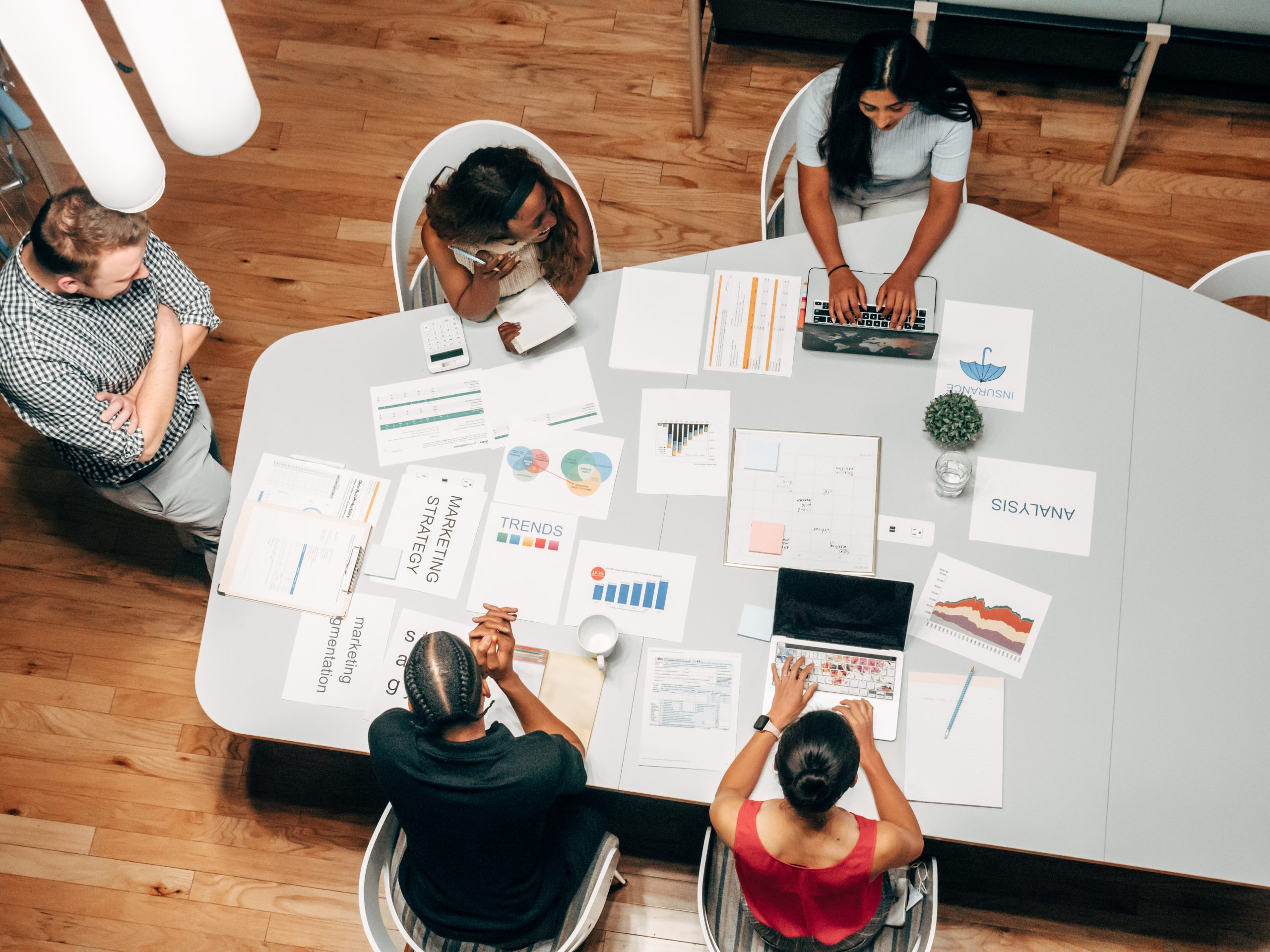 a birds eye view of business people sitting at a table working on documents and a laptop