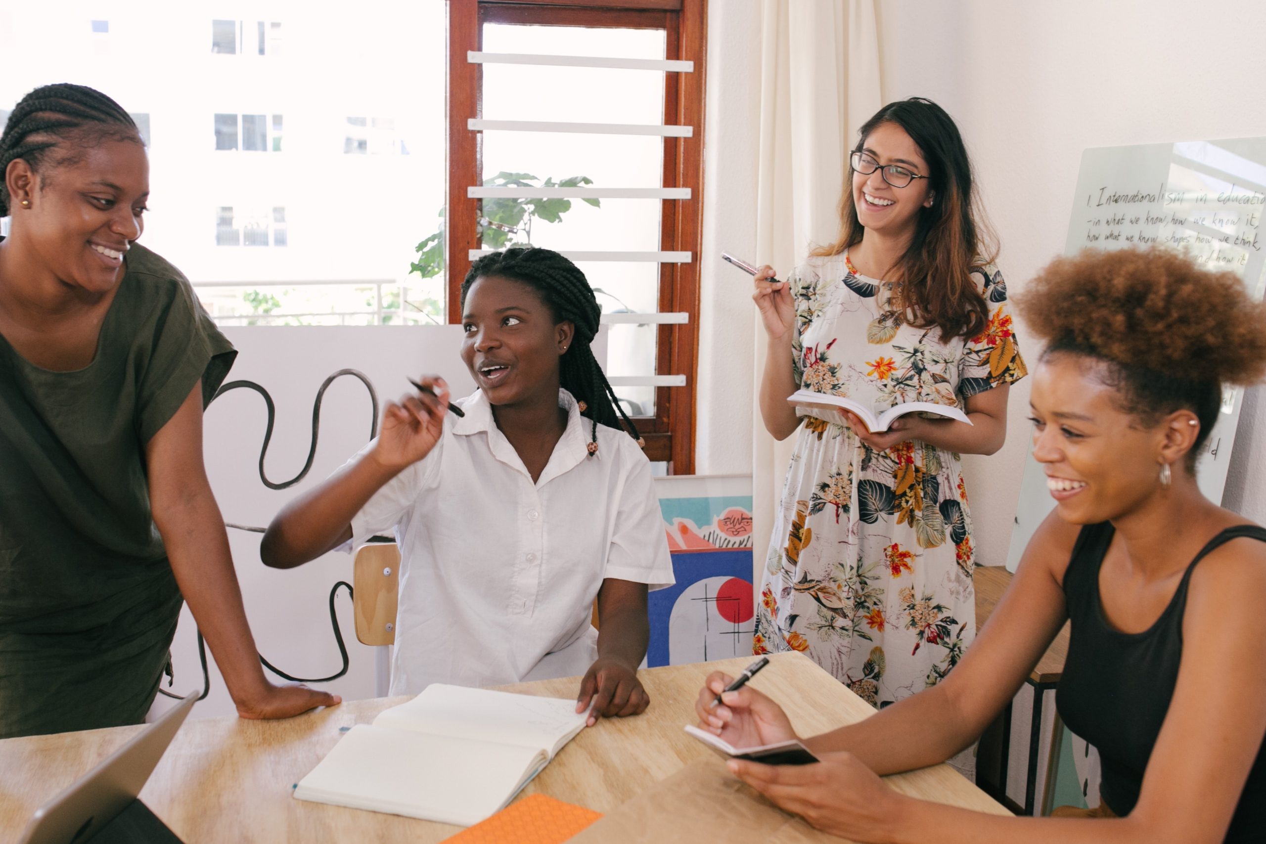 photo of four people in a room smiling possibly talking about wats to master the art of market analysis